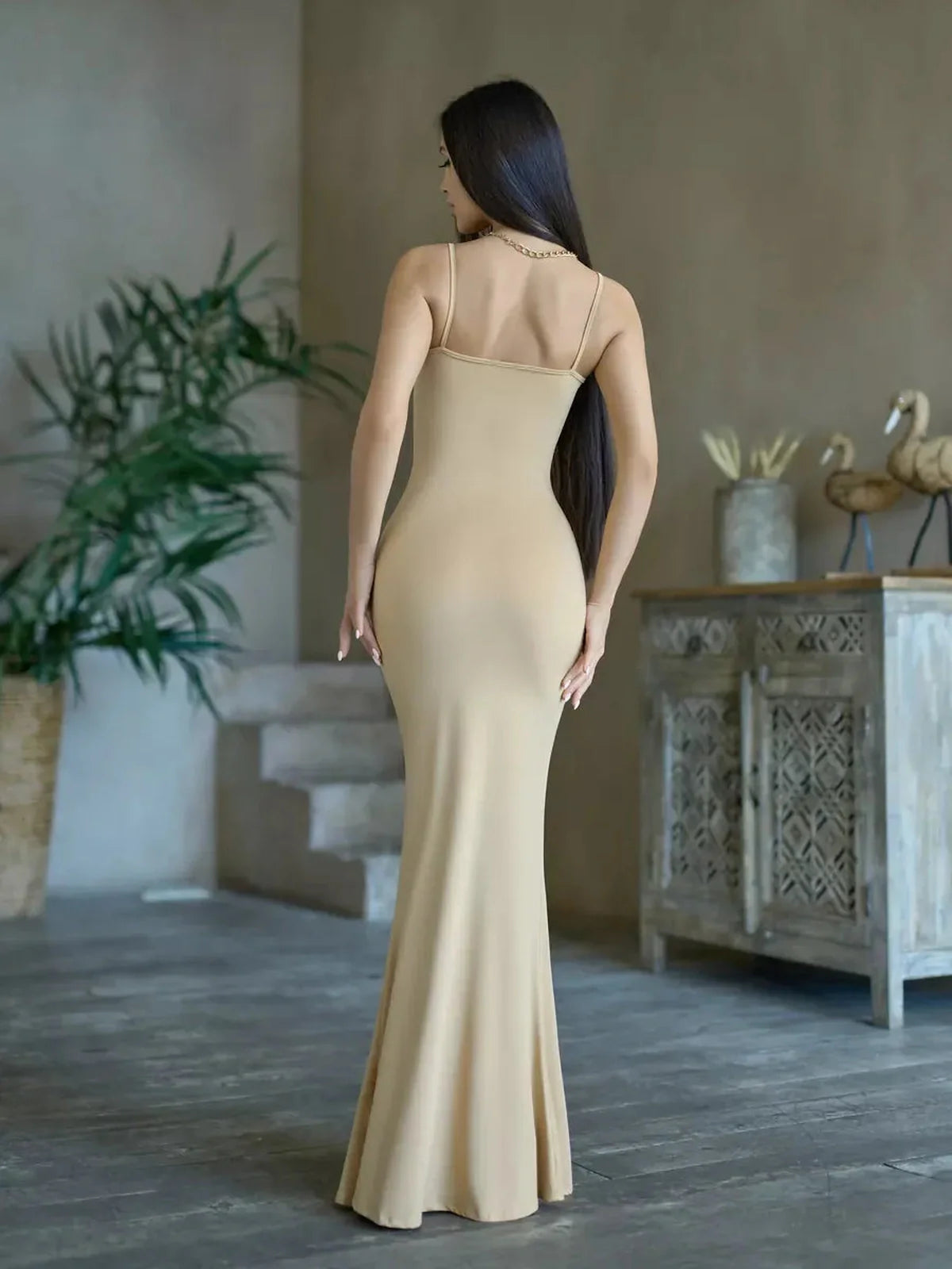 Back view of a model in a sleek, body-hugging Sculpted Elegance Maxi Dress in a minimalist, stylish setting.