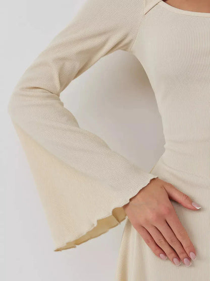 Close-up of the Sculpted Grace mini dress showing the elegant flared sleeve and textured fabric detail.