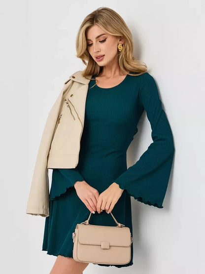Model wearing the Emerald Whisper mini dress in emerald green with flared sleeves and a stylish handbag.