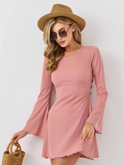 Model wearing the Blush Aura mini dress, showcasing its pink color, A-line silhouette, and flared sleeves.