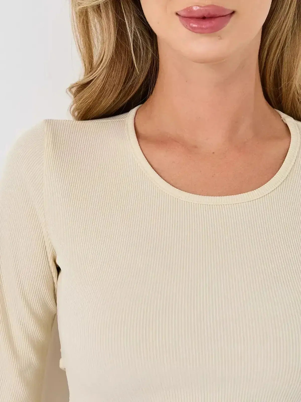 Close-up of a woman wearing an ivory ribbed long sleeve dress, showcasing its elegant neckline and texture.