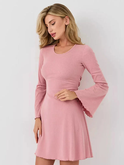 Model wearing a blush pink A-line mini dress with bell sleeves and a scoop neckline, showcasing soft elegance and refined style.
