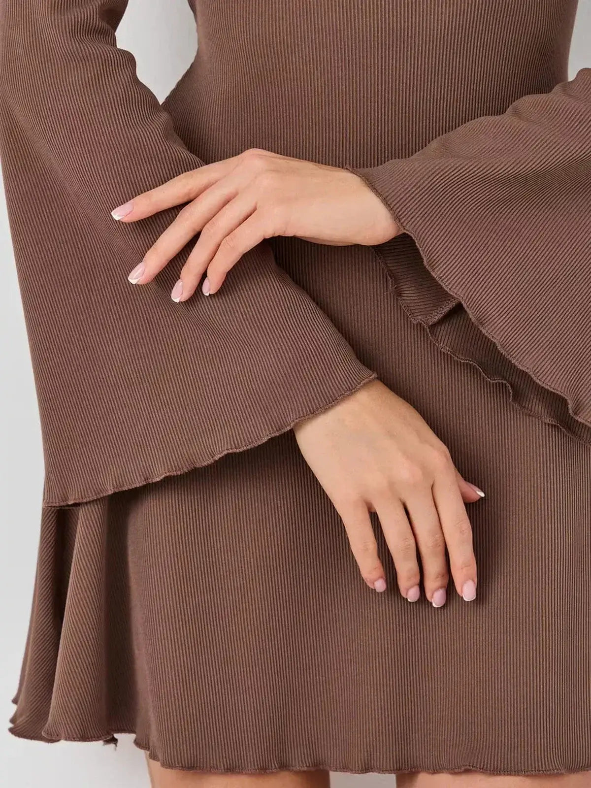 Close-up of a woman's hands showcasing the bell sleeves and soft flared hem of the Mocha Flare mini dress.