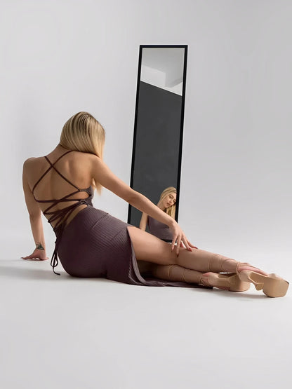 Model showcasing the Obsidian Midi Dress with strappy back and thigh-high slit, reflecting in a mirror.