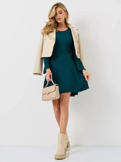 Model wearing Emerald Whisper mini dress in rich emerald green, styled with a beige jacket and handbag for an elegant look.