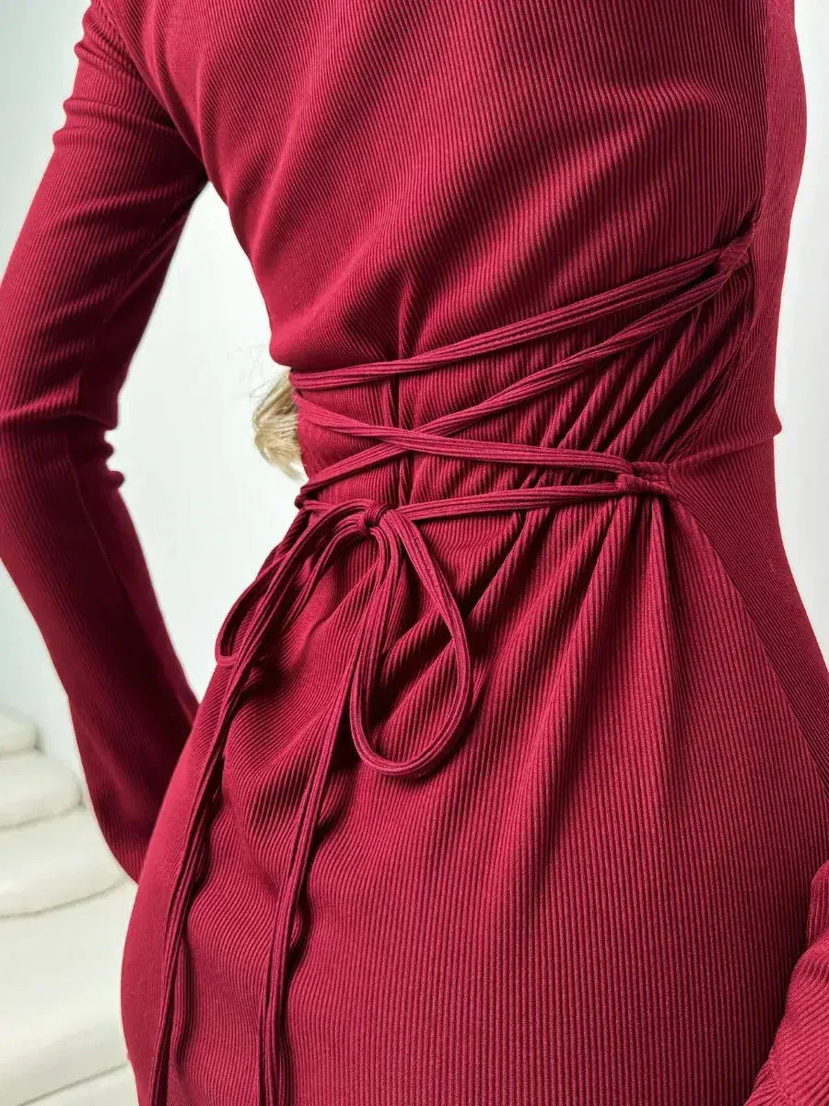 Close-up of Crimson Flare dress showcasing ribbed fabric and elegant ruffle details, highlighting a fitted silhouette.