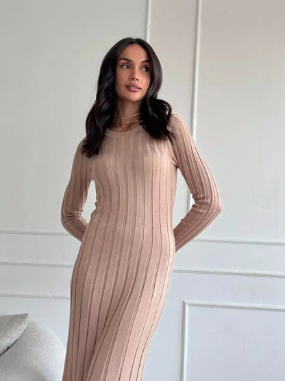 Woman in Sahara Curve Maxi Dress, showcasing soft ribbed texture and elegant silhouette in sandstone beige.