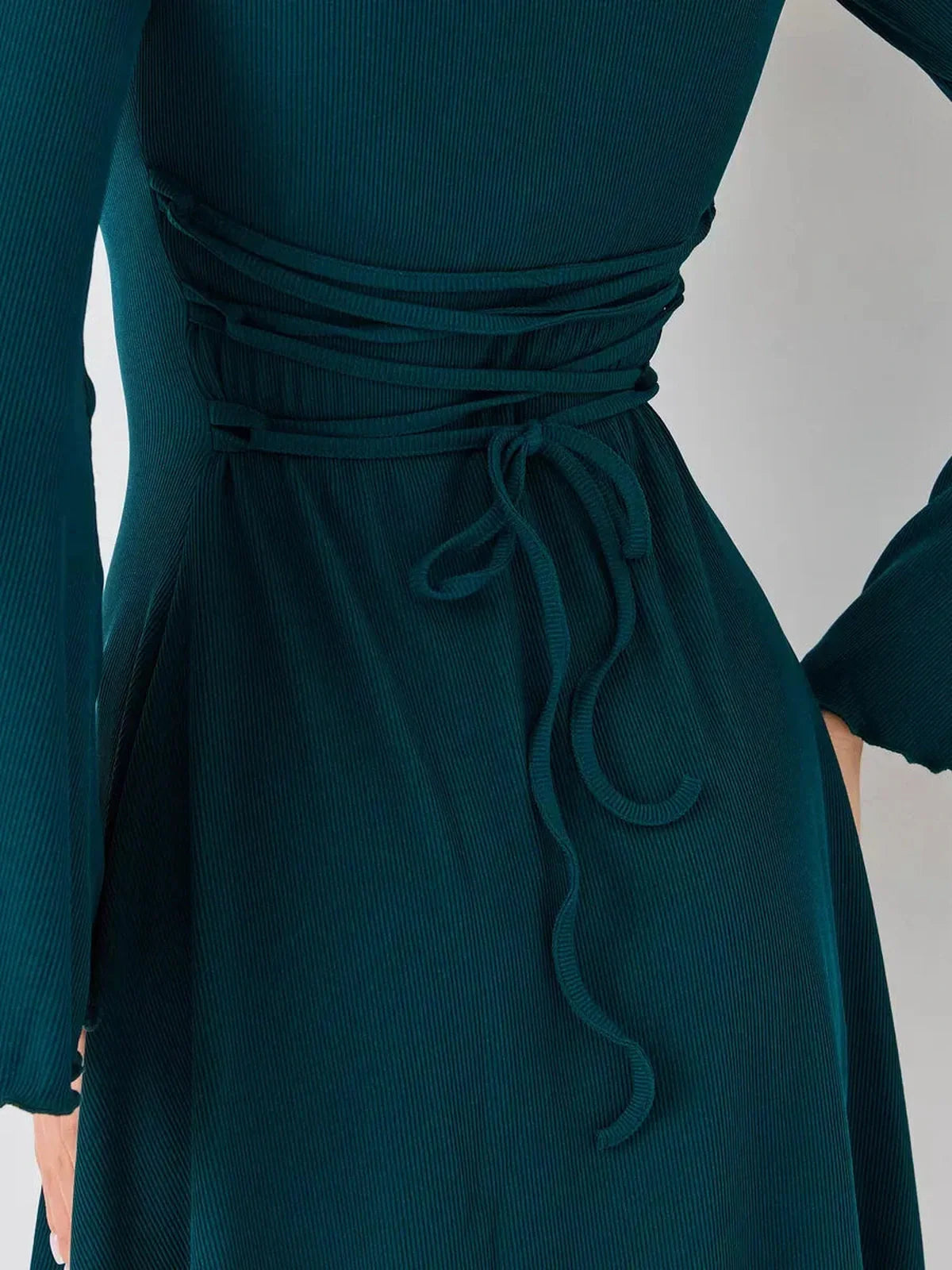 Detail of the Emerald Whisper mini dress showing its elegant tie-back feature and rich emerald green fabric.