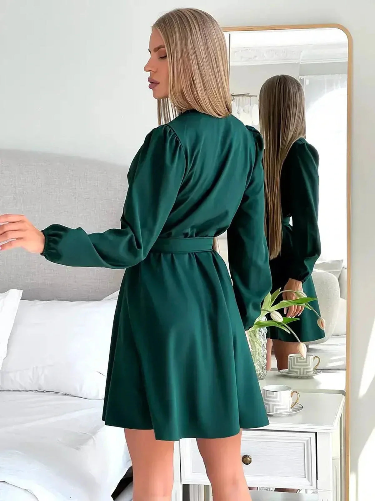 Emerald Charm mini dress featuring a wrap-style bodice, long sleeves, and a flattering silhouette in a stylish setting.