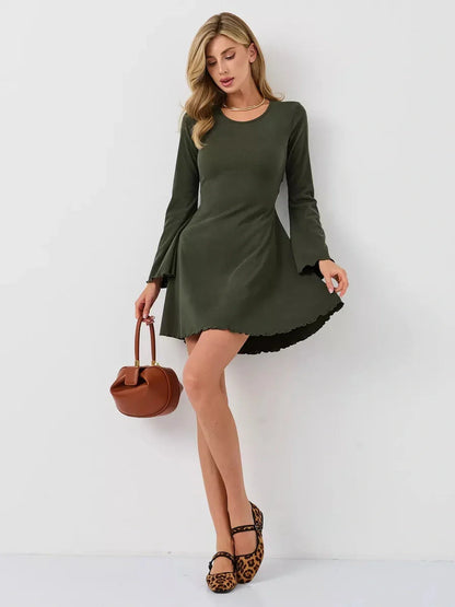 Model wearing an Ivy Bell mini dress with flared bell sleeves, in olive green, paired with a brown bag and leopard flats.