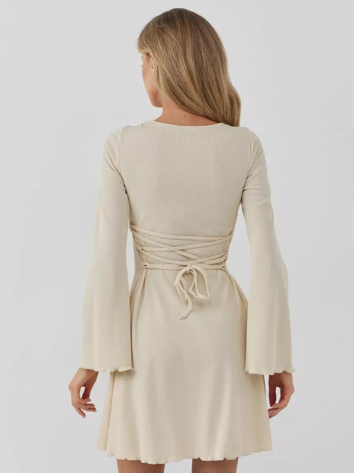 Back view of the Sculpted Grace mini dress showcasing its flared sleeves and cinched waist design.