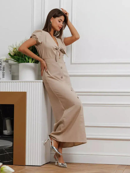Woman in Serene Bond Maxi Dress with puff sleeves, waist tie, button detail, showcasing elegance in a neutral hue.
