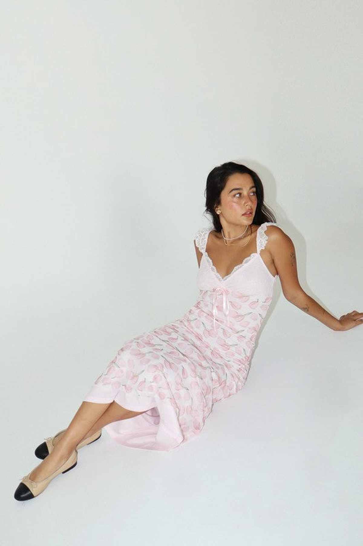 Model wearing a pink floral midi dress with lace detailing, perfect for summer occasions or as a wedding guest outfit.