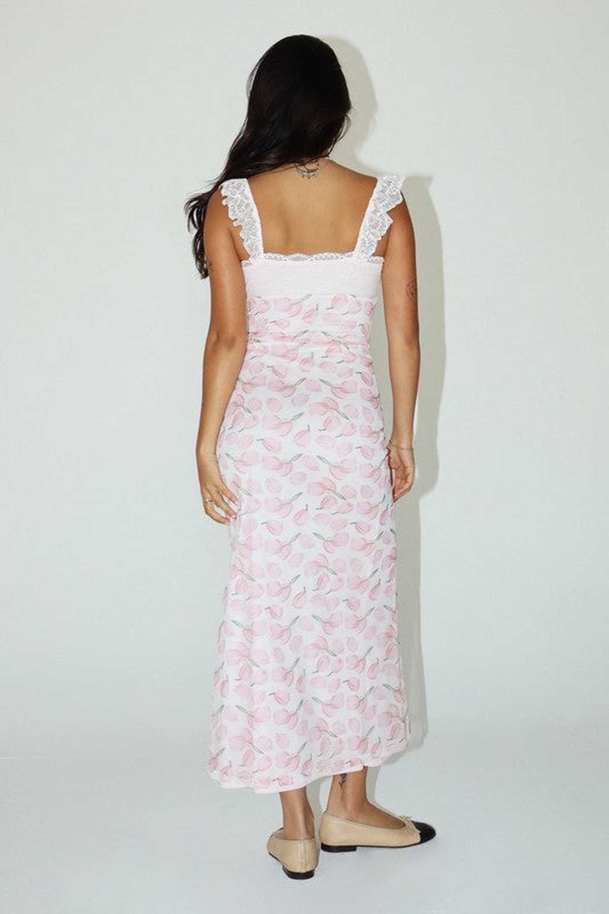 Back view of a woman in a pink floral maxi dress with lace straps, perfect for summer occasions.