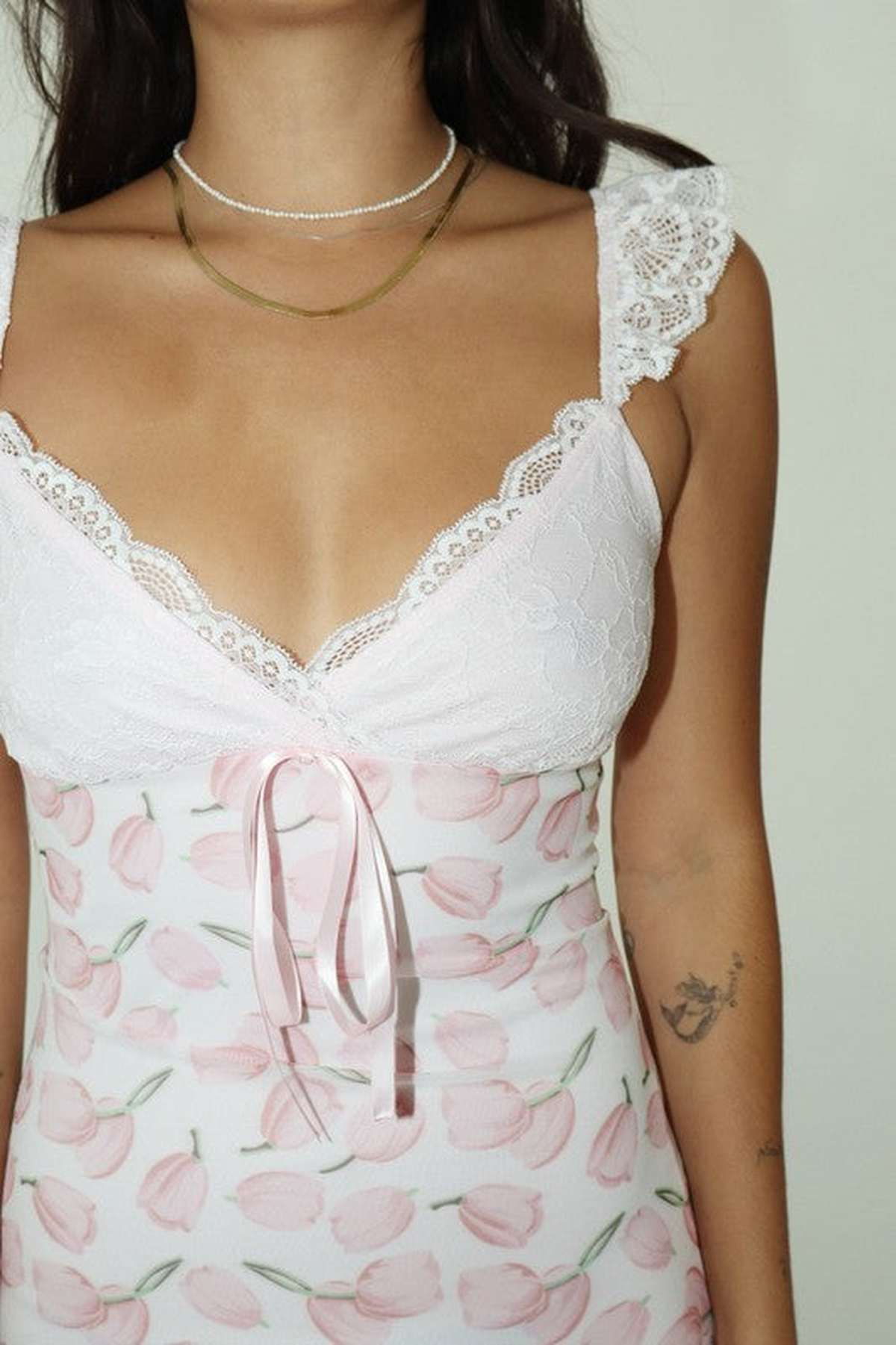 Close-up of a woman's floral dress with lace detailing and a ribbon tie, perfect for summer outings.