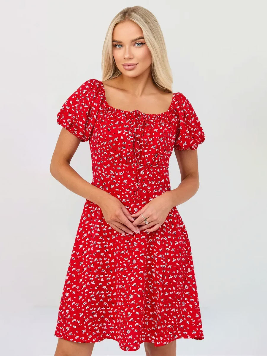 Woman in a red floral dress with puff sleeves, smiling and posing for a fashion photo.