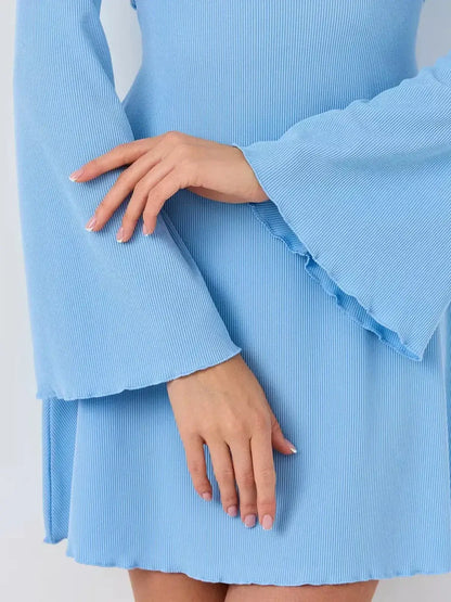 Elegant hands wearing the ribbed knit Sky Belle dress by Lauven, showcasing its flared sleeves and pastel blue fabric.
