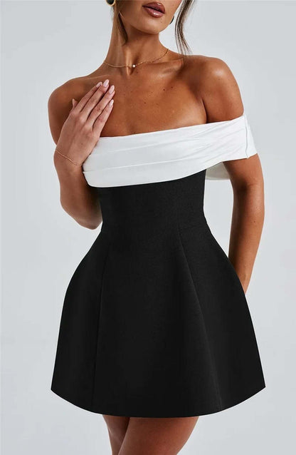 Elegant black and white off-shoulder mini dress featuring an oversized bow, perfect for wedding guests or parties.