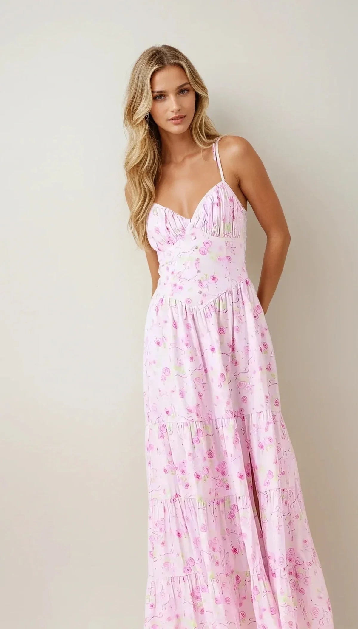 Model wearing the Amélie Dress, a pink floral maxi dress with spaghetti straps and a ruched bust.