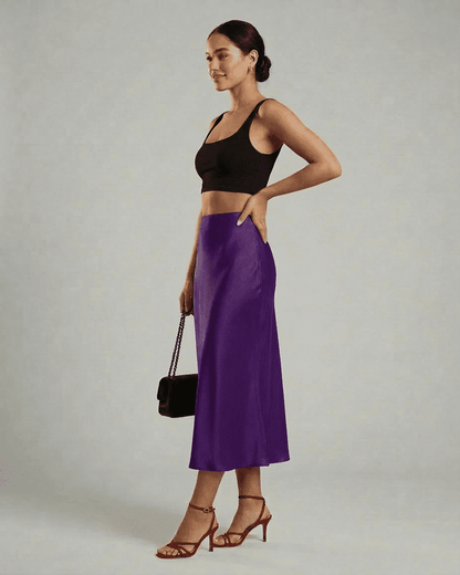 Model showcasing Lauven Amethyst Midi Skirt in vibrant purple, paired with a black crop top and red heels.