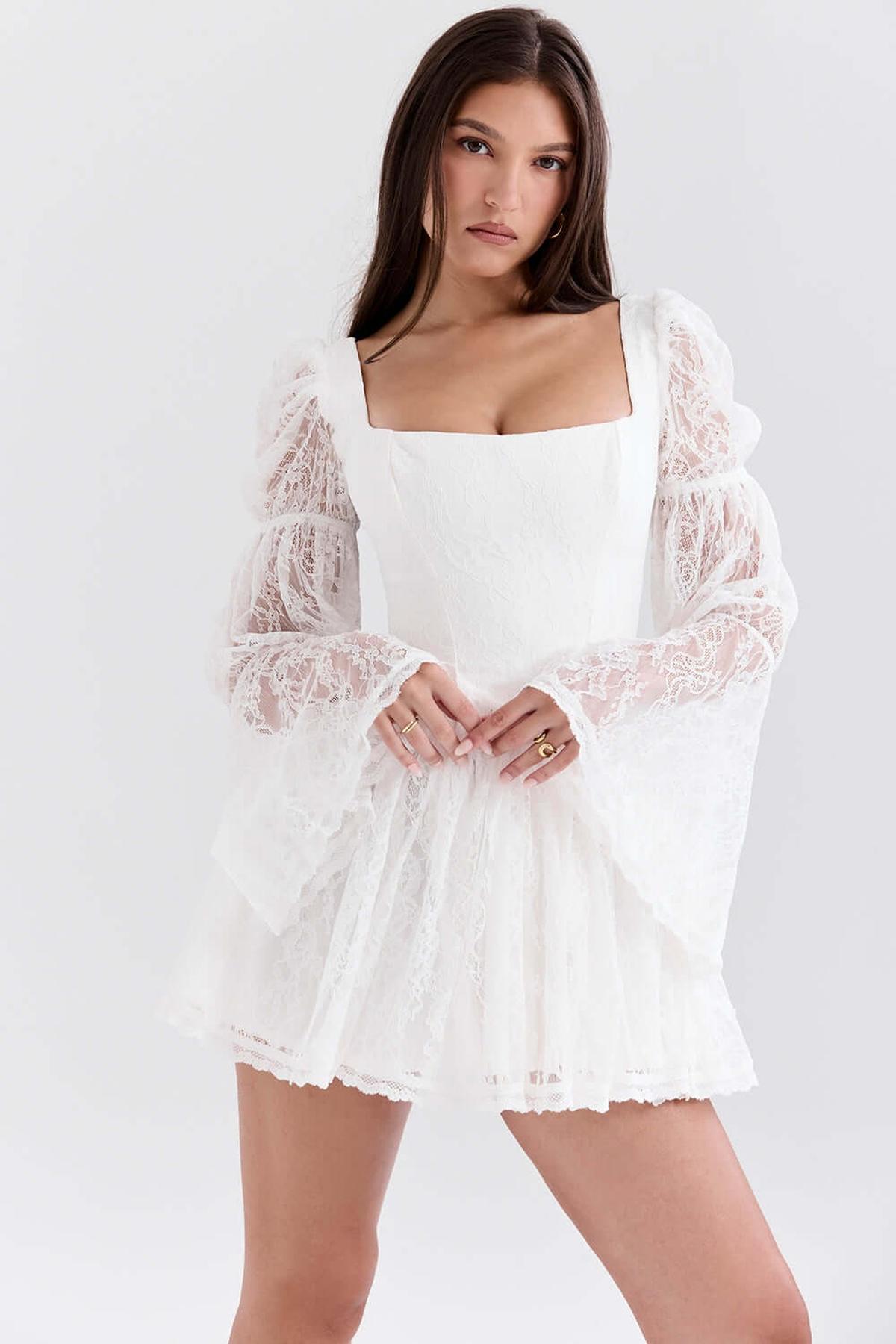 Model wearing the Angel Mini Dress, a white mini dress with lace puff sleeves, perfect for weddings and summer events.