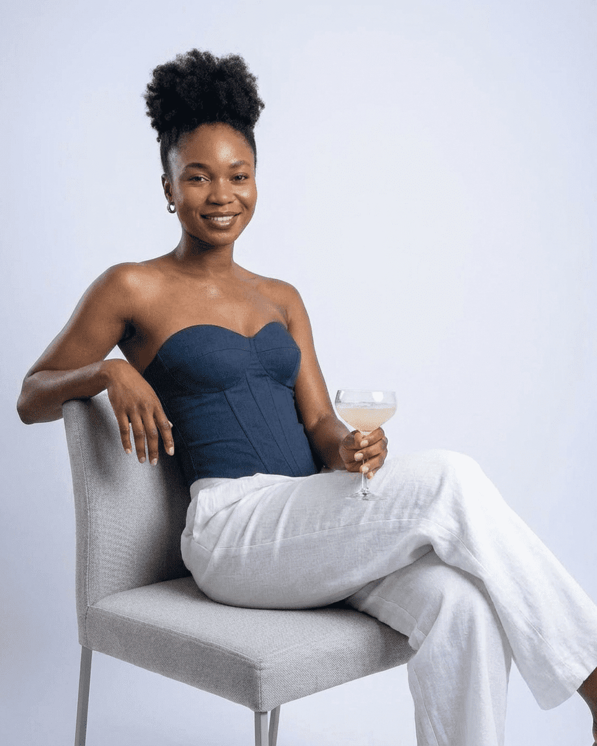 Model wearing Atlas Corset Top by Lauven, a navy faux denim cup bustier styled with elegant white pants.