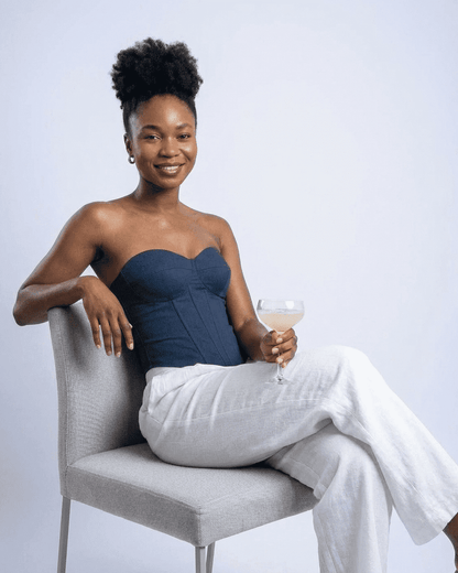 Model wearing Atlas Corset Top by Lauven, a navy faux denim cup bustier styled with elegant white pants.