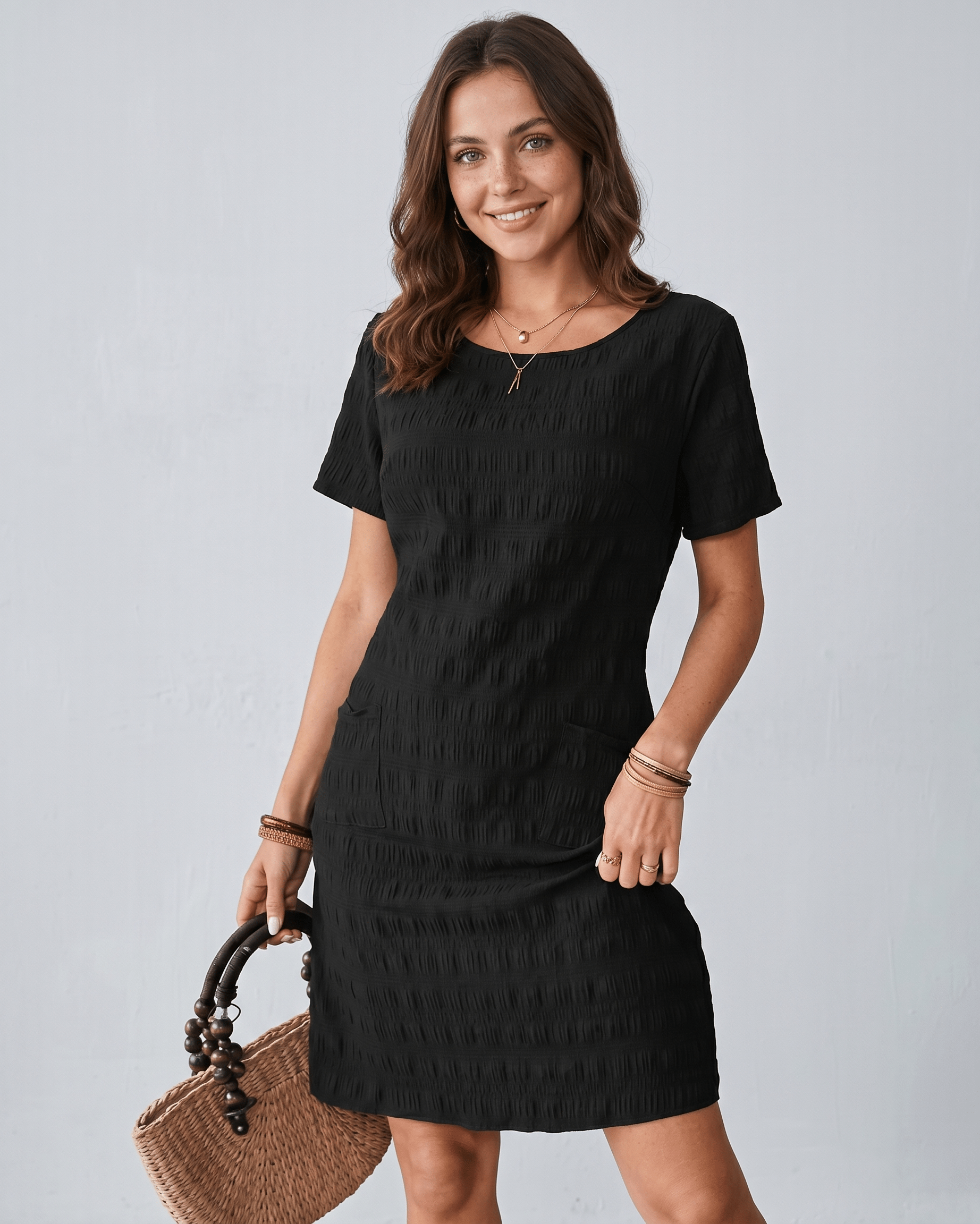 Avelin Mini Dress with textured fabric, round neckline, short sleeves, worn with a straw bag, Lauven brand style.