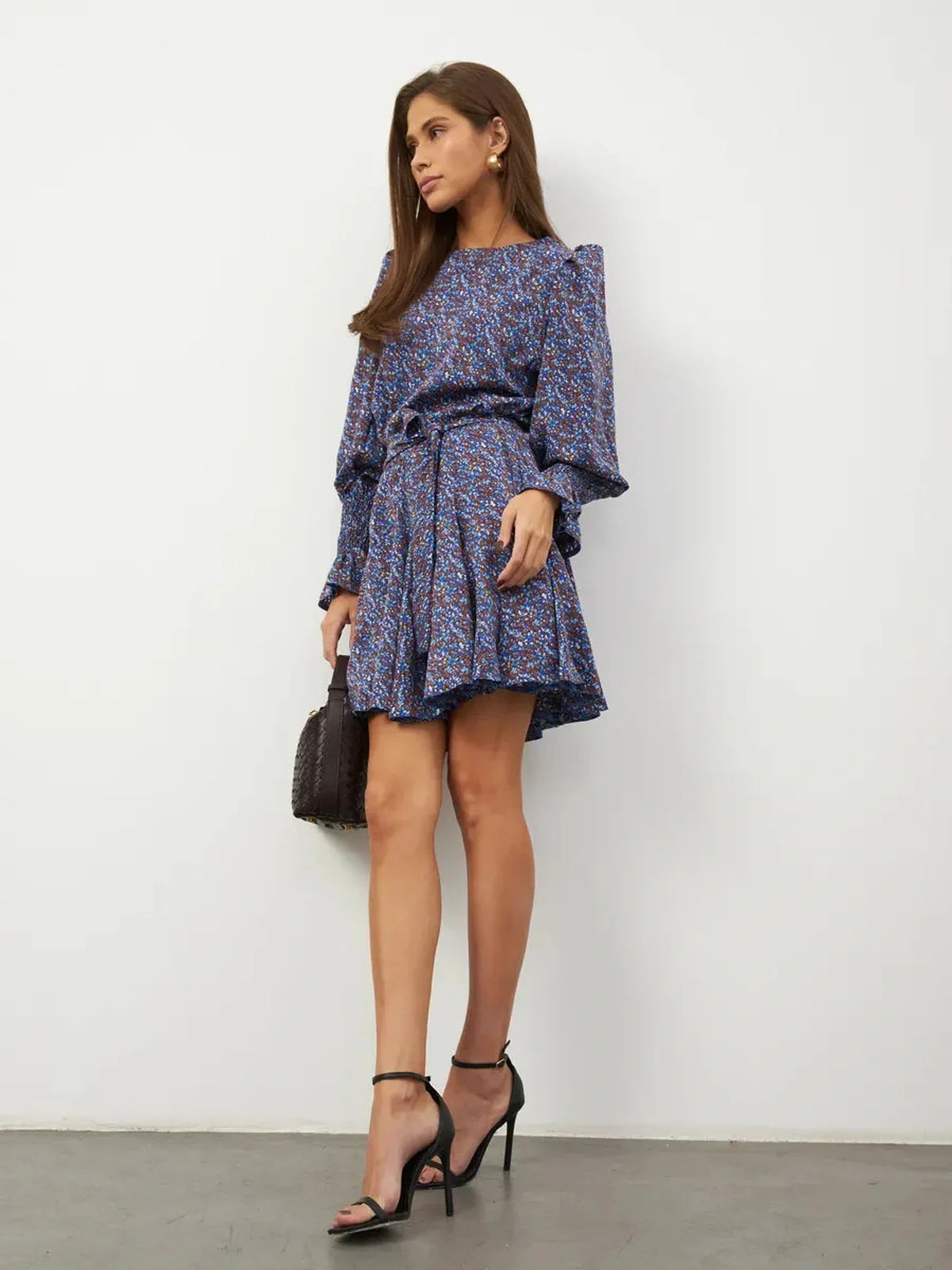 Model wearing Azure Bloom Mini Dress with blue floral patterns, ruffled cuffs, and a flattering silhouette.