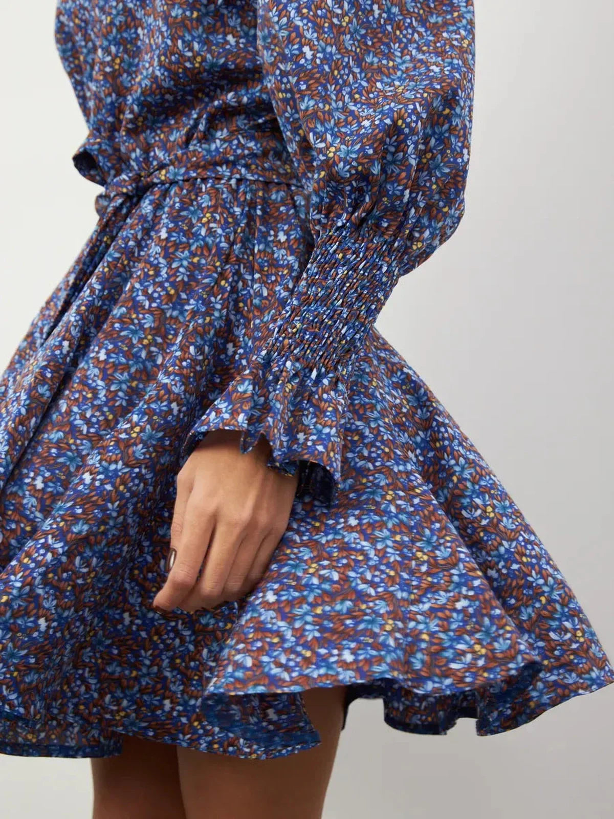 Close-up of the Azure Bloom Mini Dress showcasing vibrant blue floral patterns and ruffled hem detail.