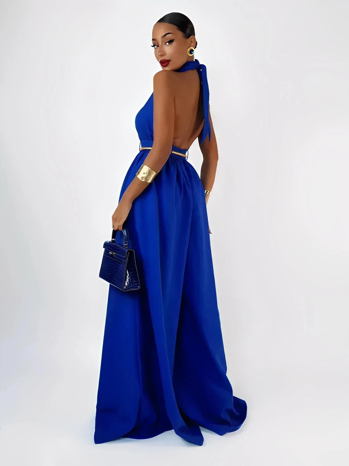 Elegant woman in a blue halter jumpsuit with a wide leg silhouette and open back, perfect for summer events.