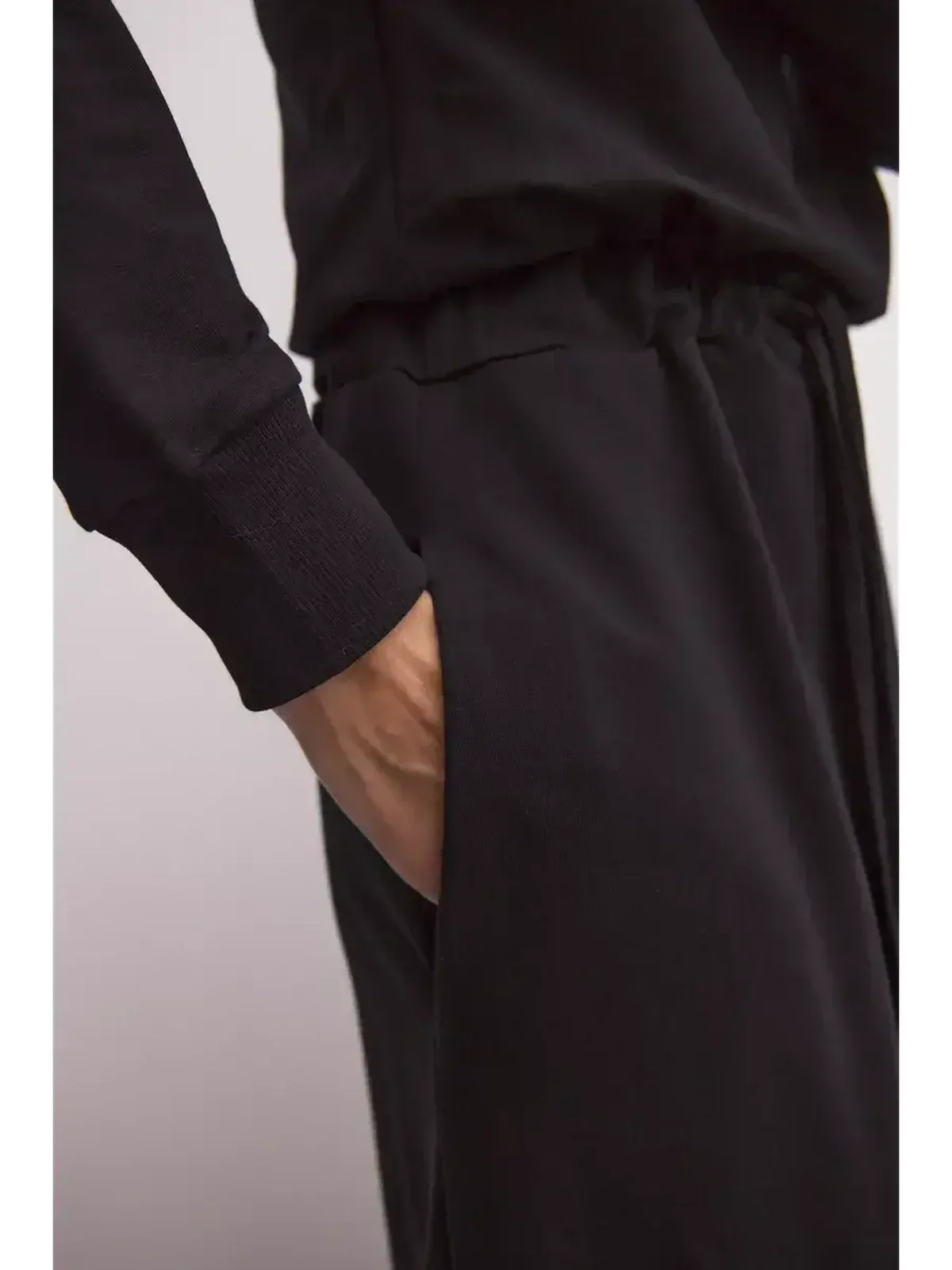 Close-up of a hand in the pocket of a black maxi dress, showcasing sleek comfort and modern design.