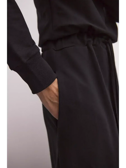 Close-up of a hand in the pocket of a black maxi dress, showcasing sleek comfort and modern design.