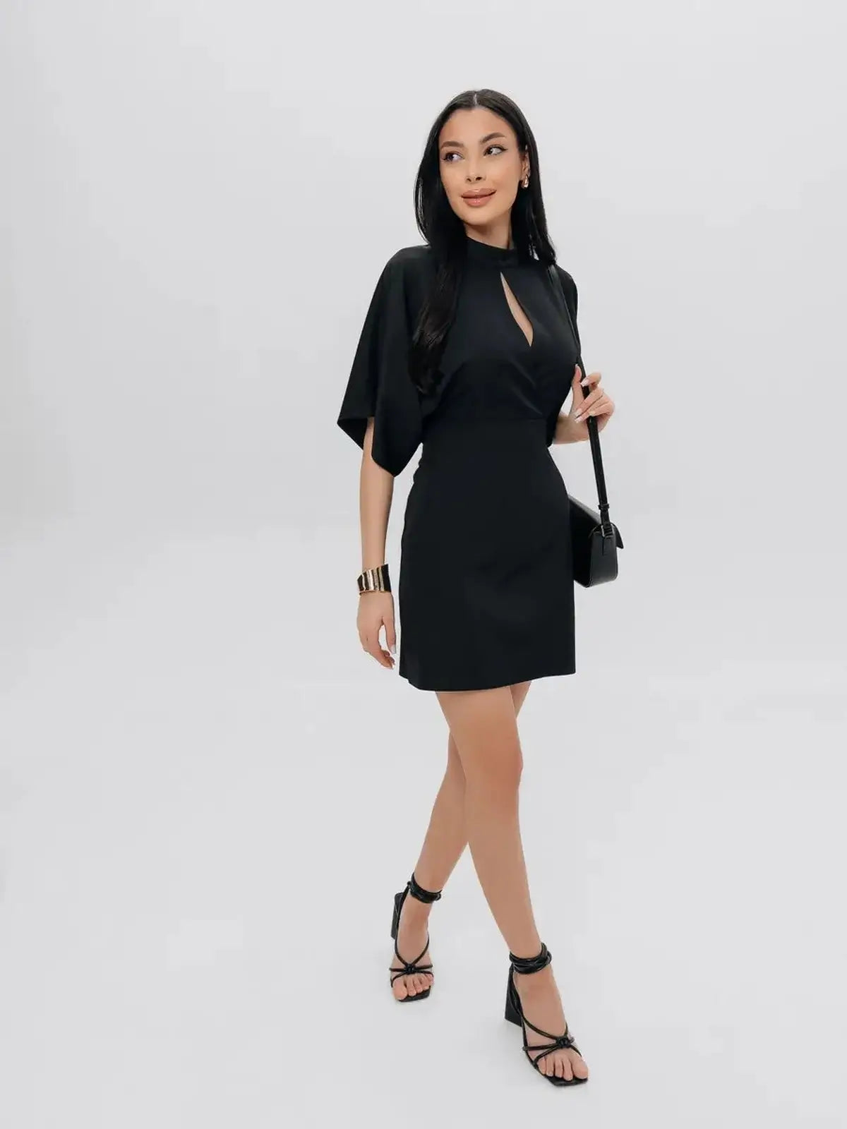 Model wearing the Shadow Grace black mini dress with high neckline and winged short sleeves, perfect for cocktail events.
