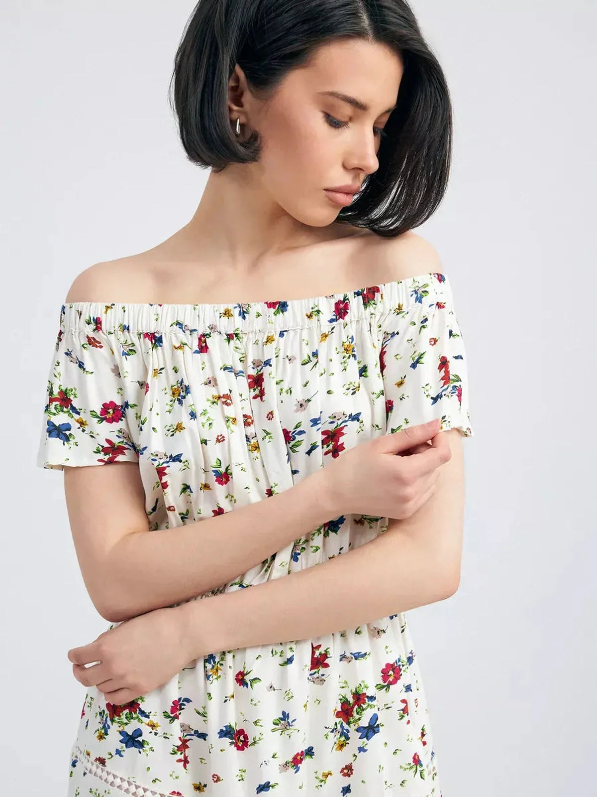 Woman wearing the Bloom Off-Shoulder dress, featuring a floral print and an elegant Carmen neckline.