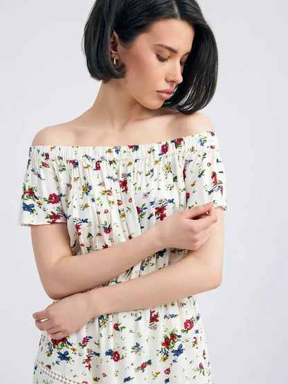 Woman wearing the Bloom Off-Shoulder dress, featuring a floral print and an elegant Carmen neckline.