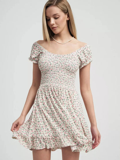 Model wearing a romantic Blush Blossom summer dress with pink floral prints and a ruffled hem.