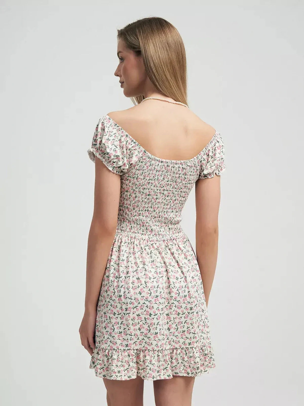 Back view of a feminine Blush Blossom summer dress with pink floral prints and a ruffled hem, ideal for garden parties.