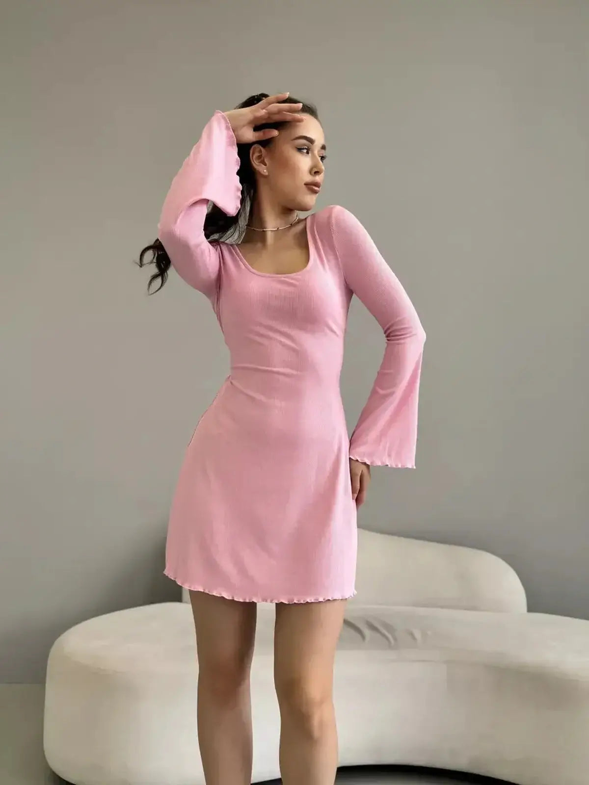 Model showcasing Blush Hour mini dress in soft pink, featuring a square neckline and bell cuffs, perfect for summer events.
