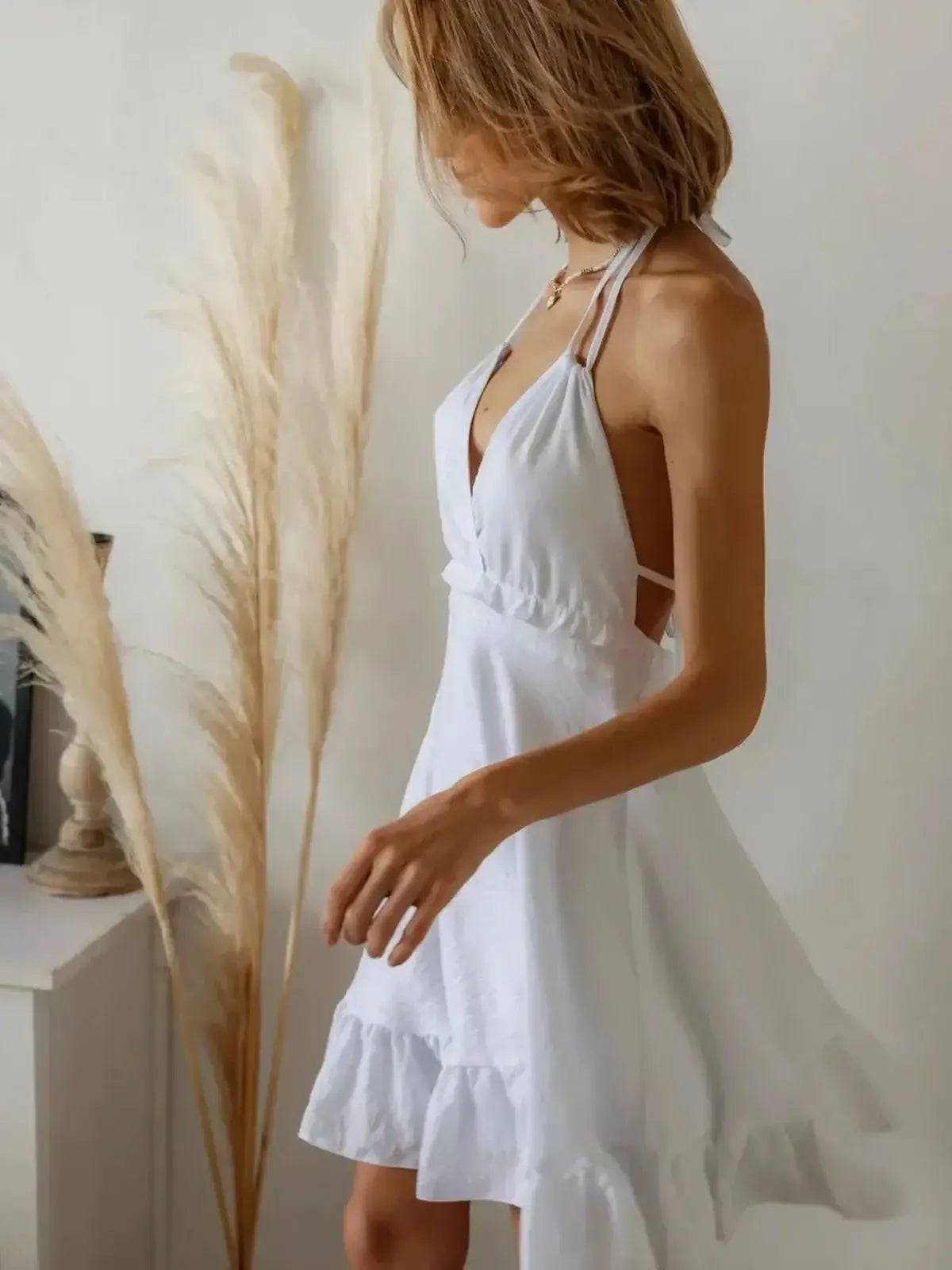 Model showcasing the Breeze Halter, a chic white summer dress with a flattering halter neckline and flowing skirt.