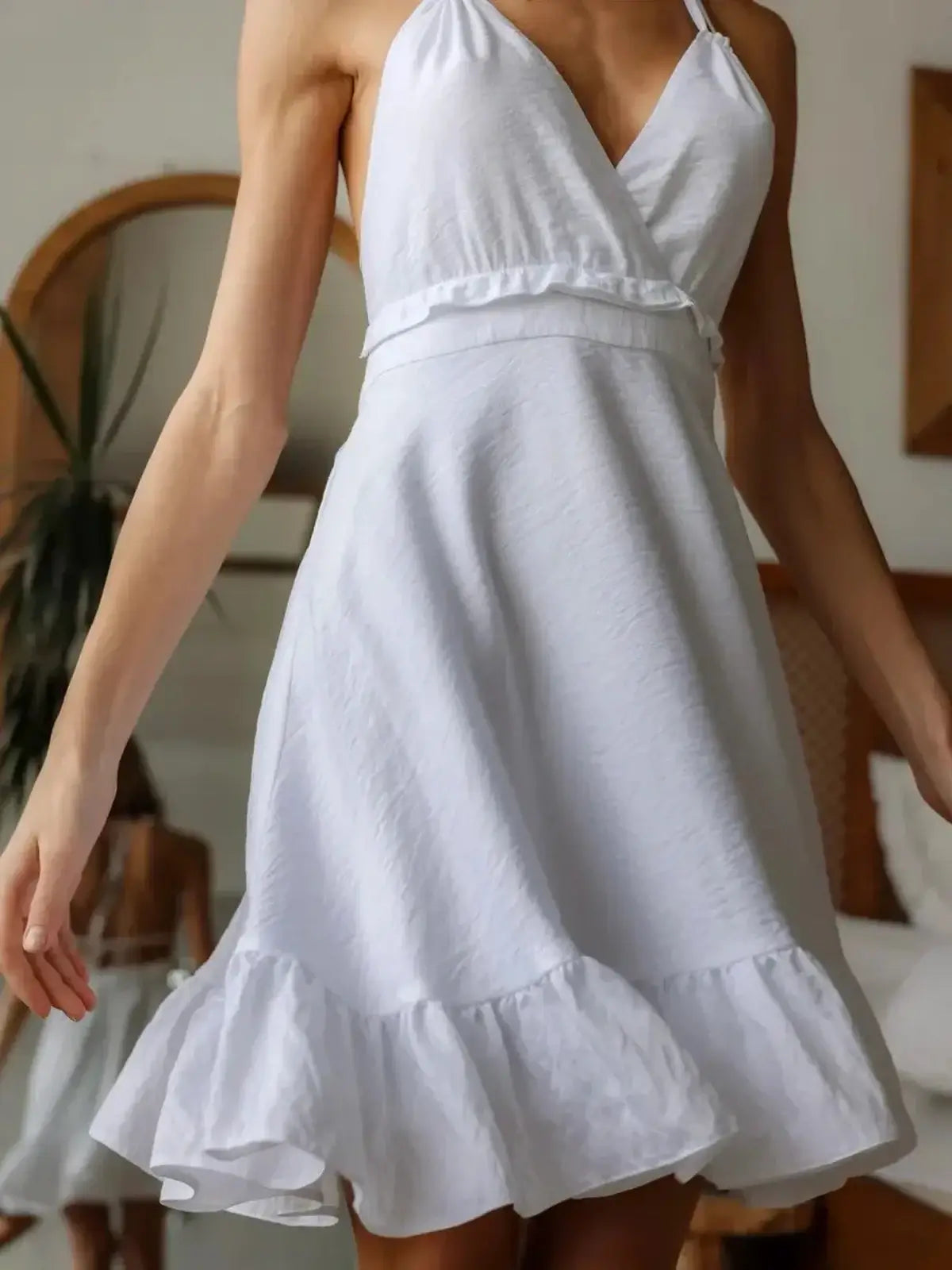 Stylish woman wearing the Breeze Halter white dress, perfect for summer occasions, featuring a flattering design and ruffled hem.