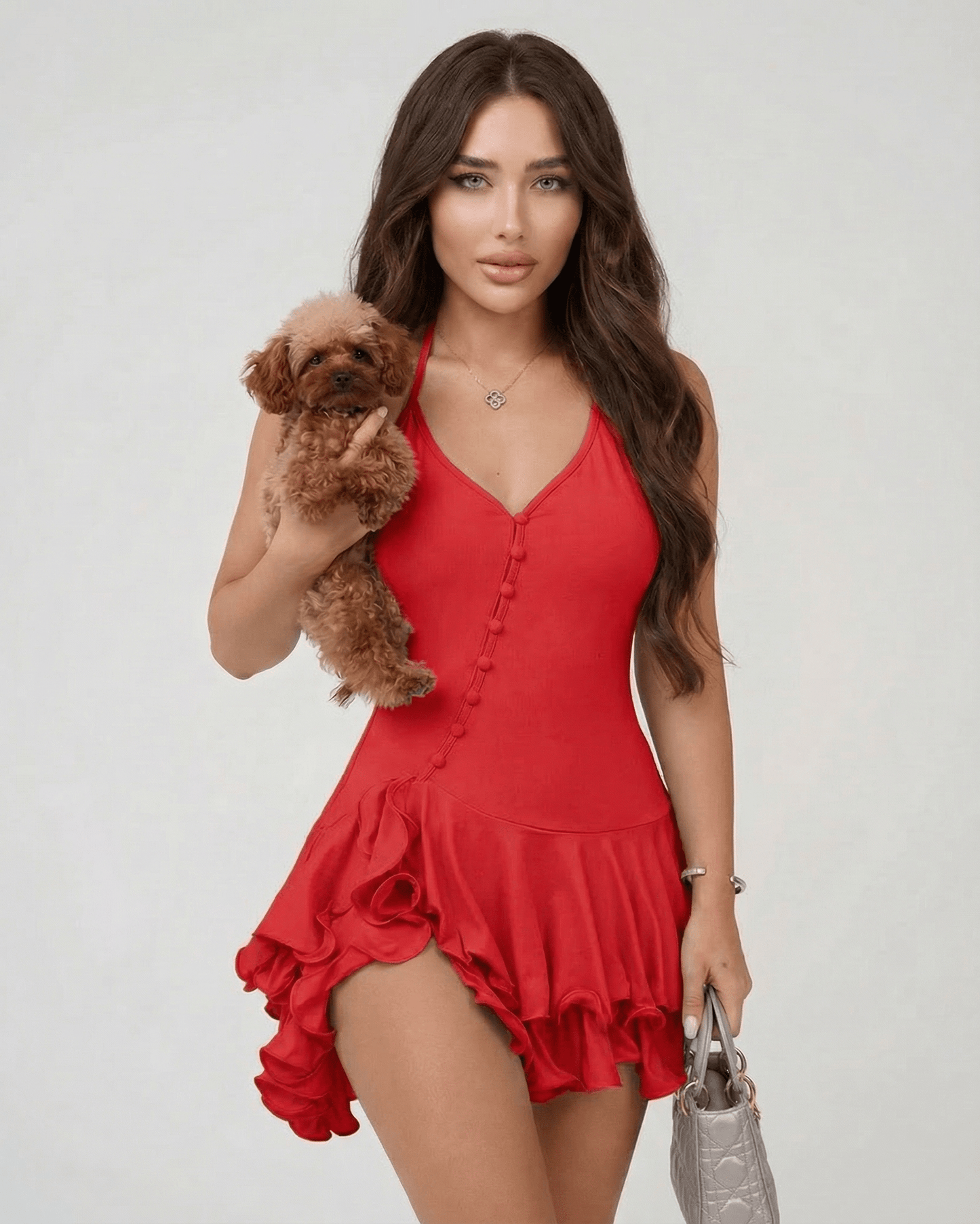 Model wearing Calista Mini Dress by Lauven, holding a small dog, showcasing the red halter neck and ruffle hem.