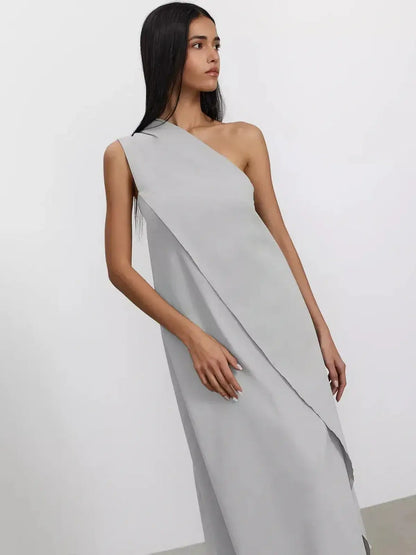 Model wearing the Cascade Maxi Dress in soft gray, showcasing its one-shoulder silhouette and flowing A-line design.