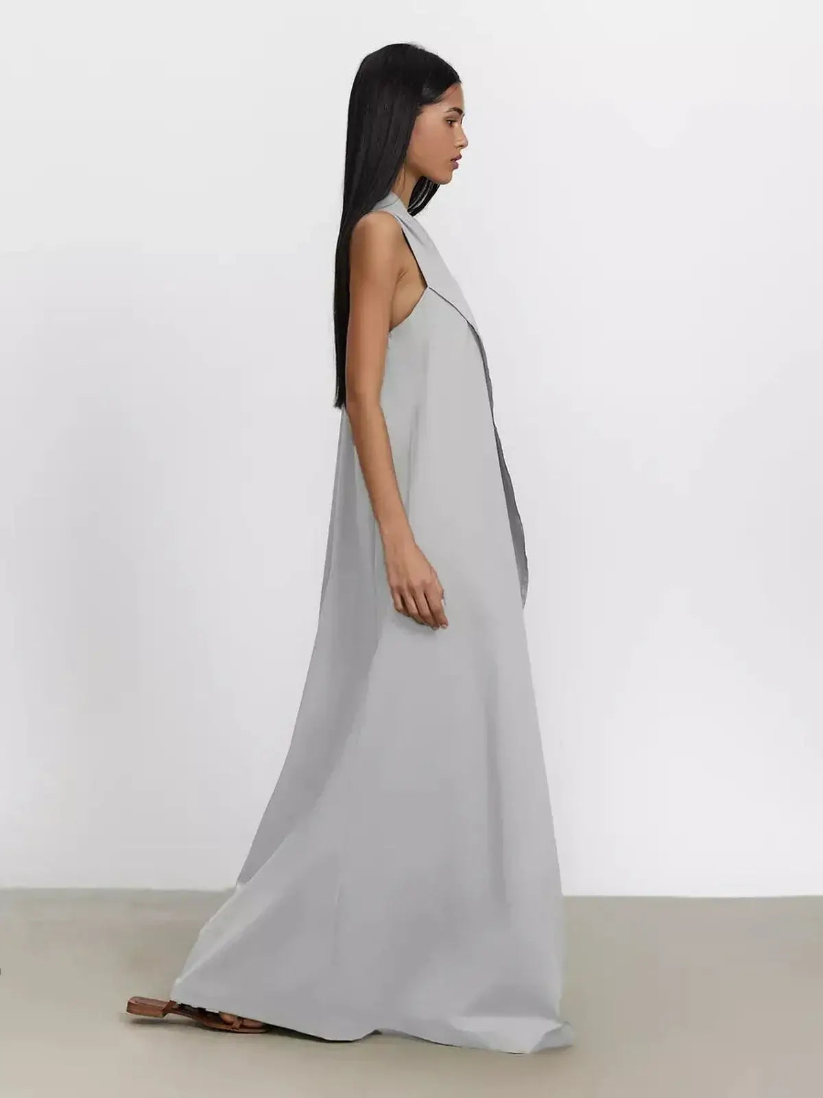 Side view of a model wearing a grey Cascade Maxi Dress featuring a one-shoulder silhouette in breathable cotton.