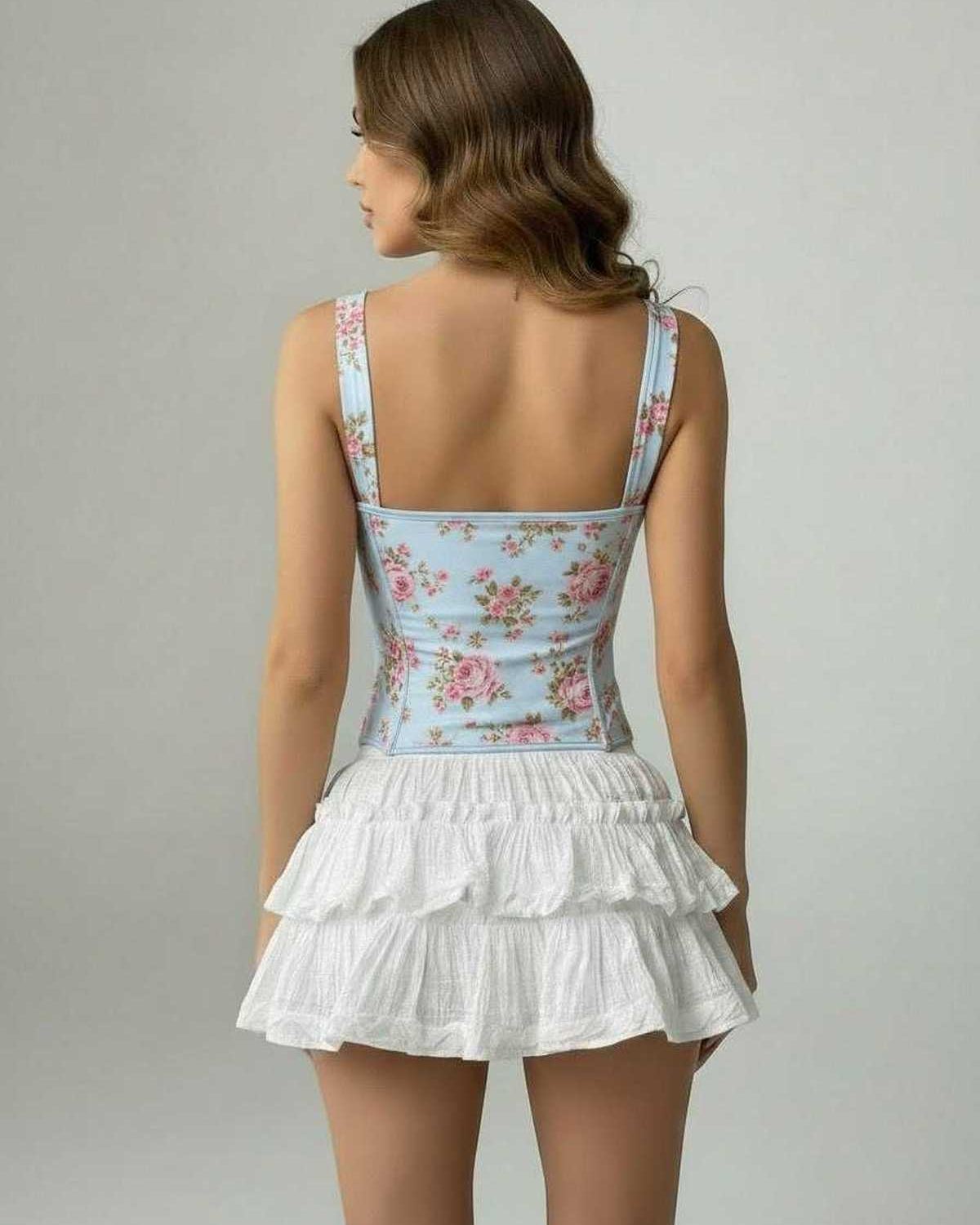 Back view of a woman wearing the Celeste Corset Top by Lauven with a white ruffled skirt, featuring a floral design.