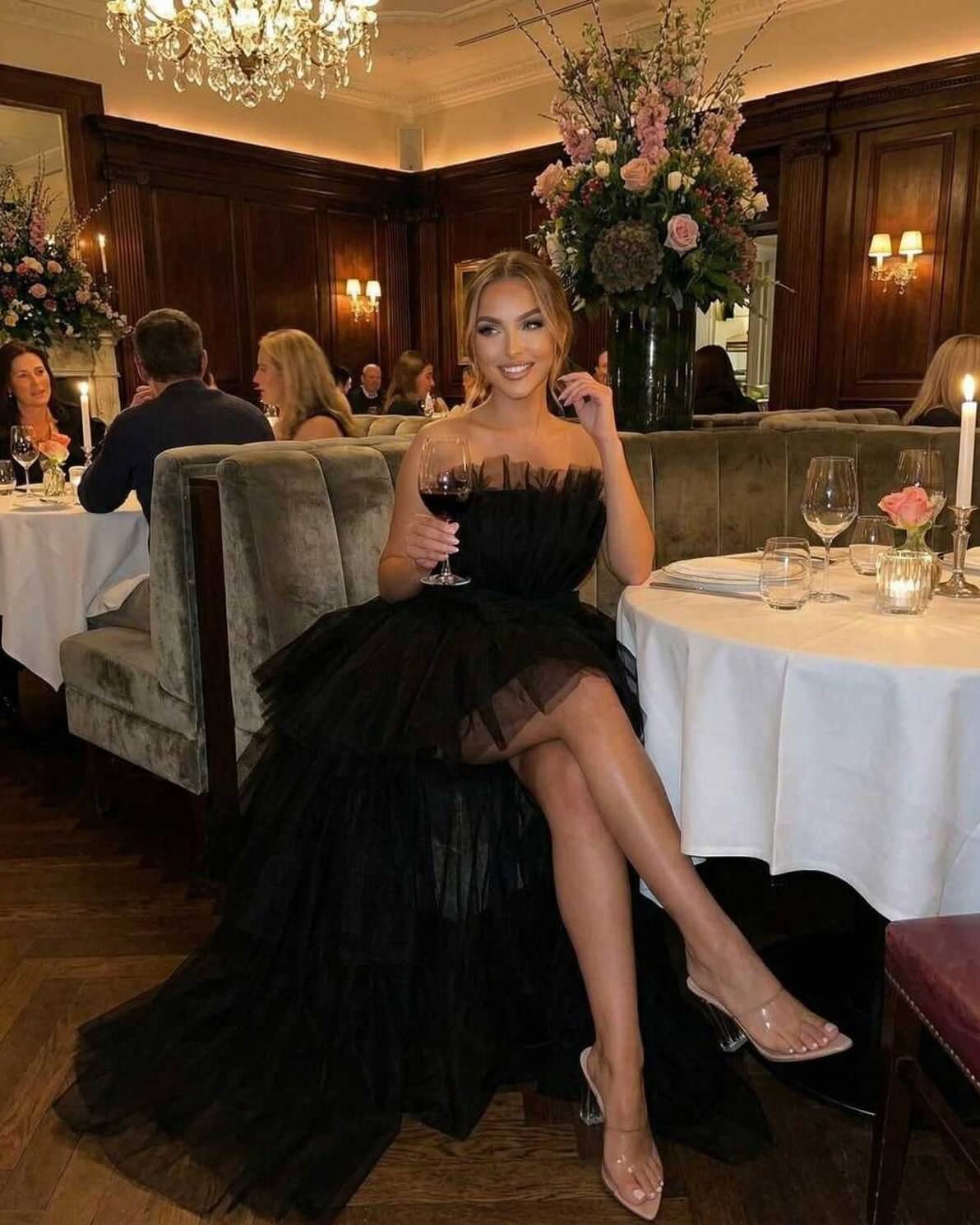 Celeste Maxi Dress by Lauven features a strapless design with a dramatic tulle overlay, styled at an elegant dining setting.