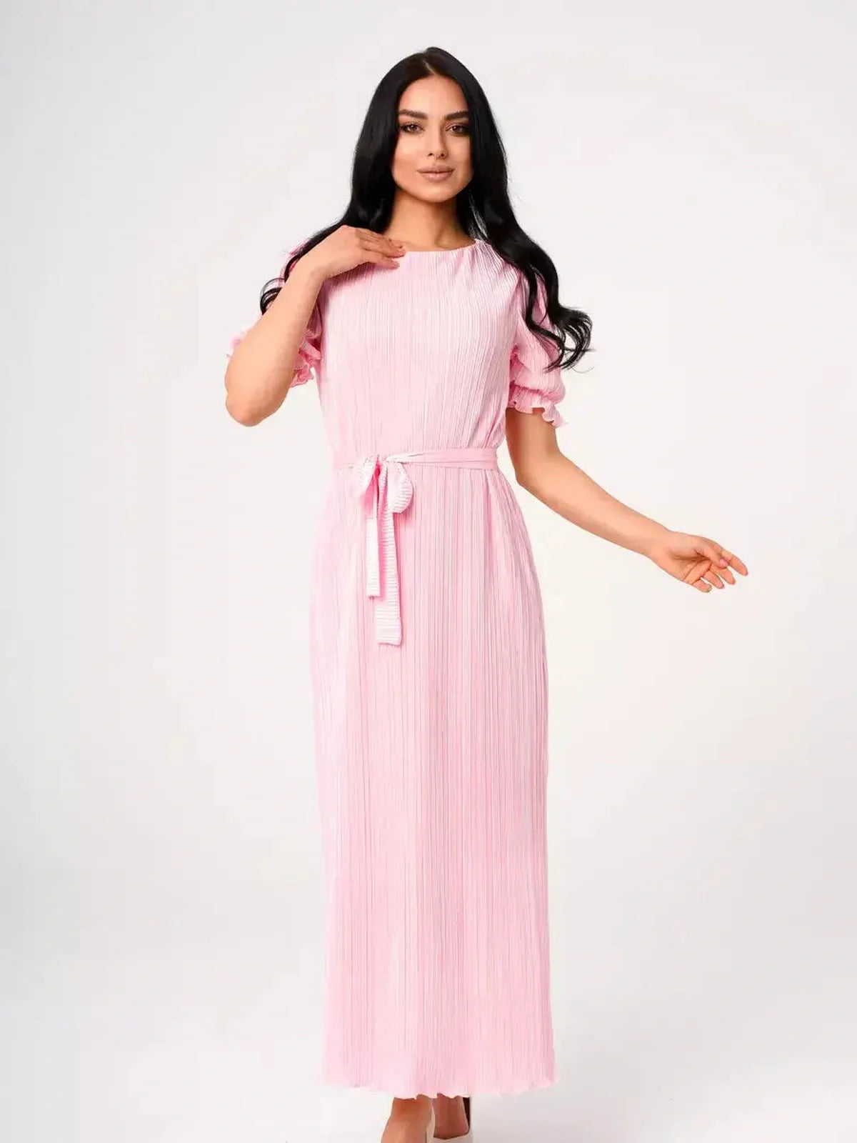 Model showcasing the Celeste Maxi Dress in pink, featuring pleated fabric, puff sleeves, and a tie waist, perfect for summer events.