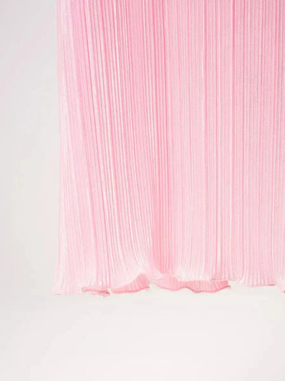 Pleated pink fabric of a maxi dress, showcasing elegant texture and flow, ideal for summer and formal occasions.