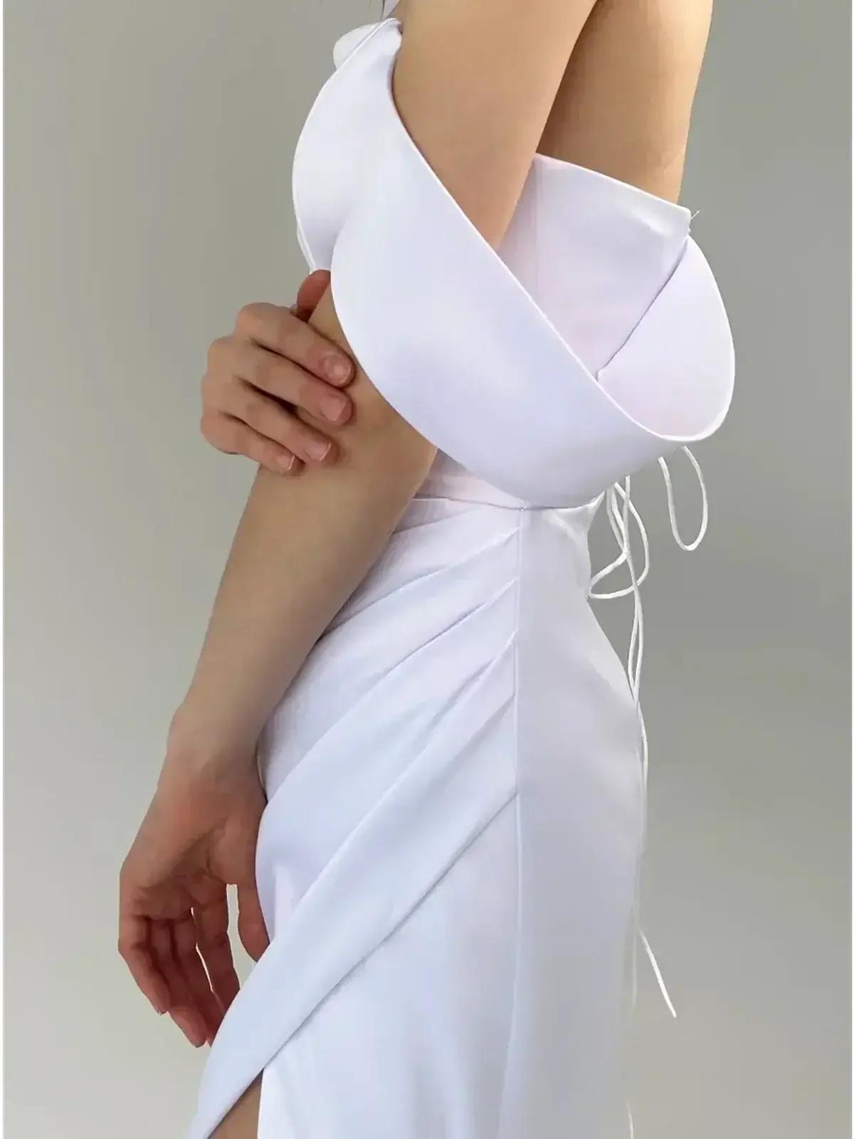 Detail of the Celeste Maxi Dress highlighting the off-shoulder design and corset-inspired lace-up back in elegant white fabric.