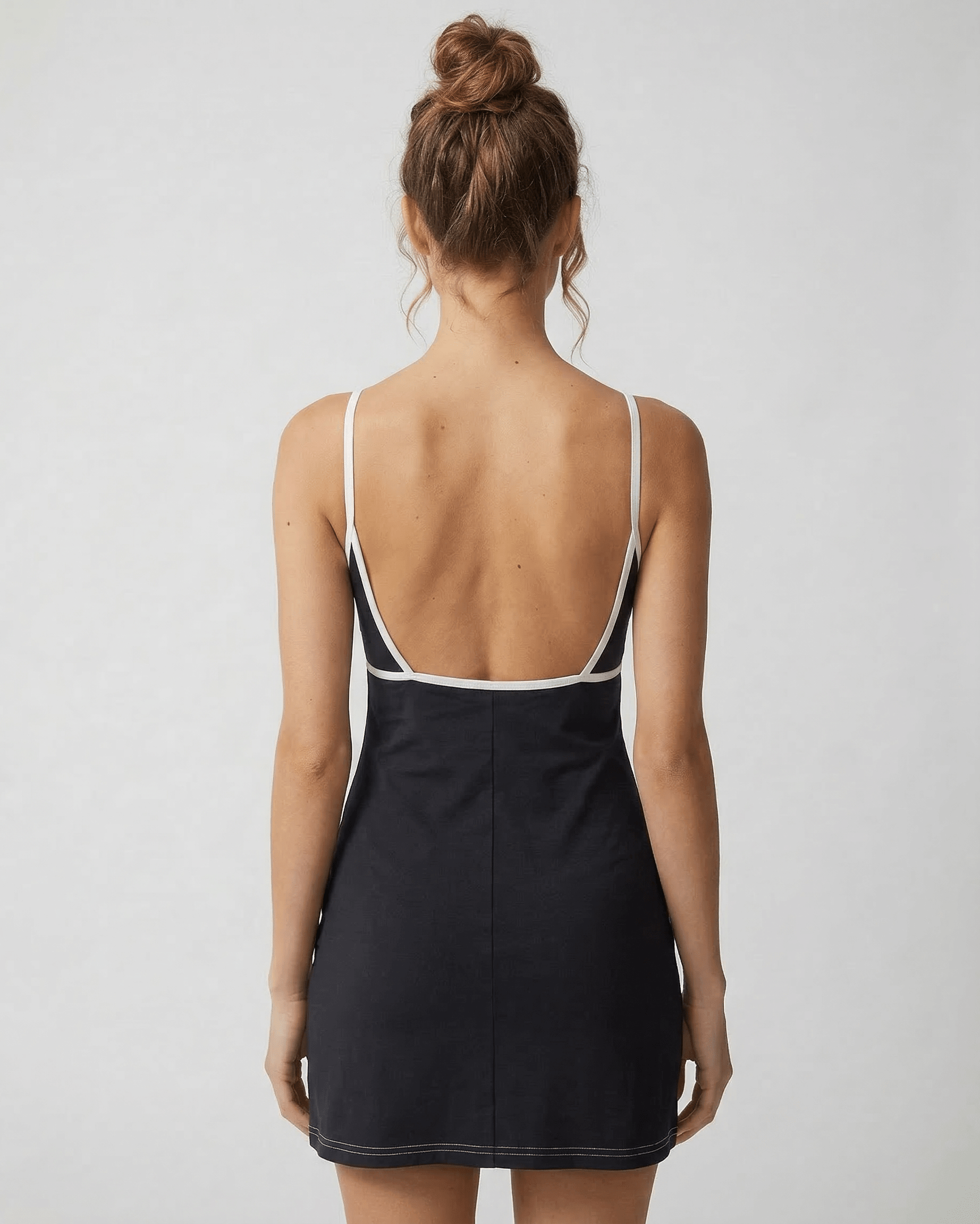 Back view of a model wearing the Celeste Mini Dress by Lauven, showcasing its sleek cut-out detail and flattering fit.